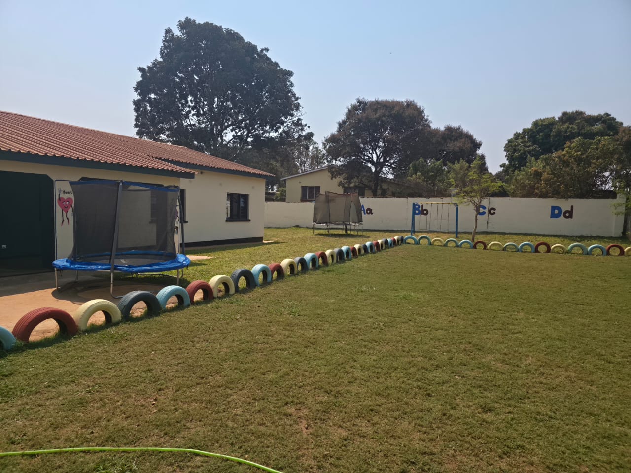 Green playing field with swings and alphabet wall